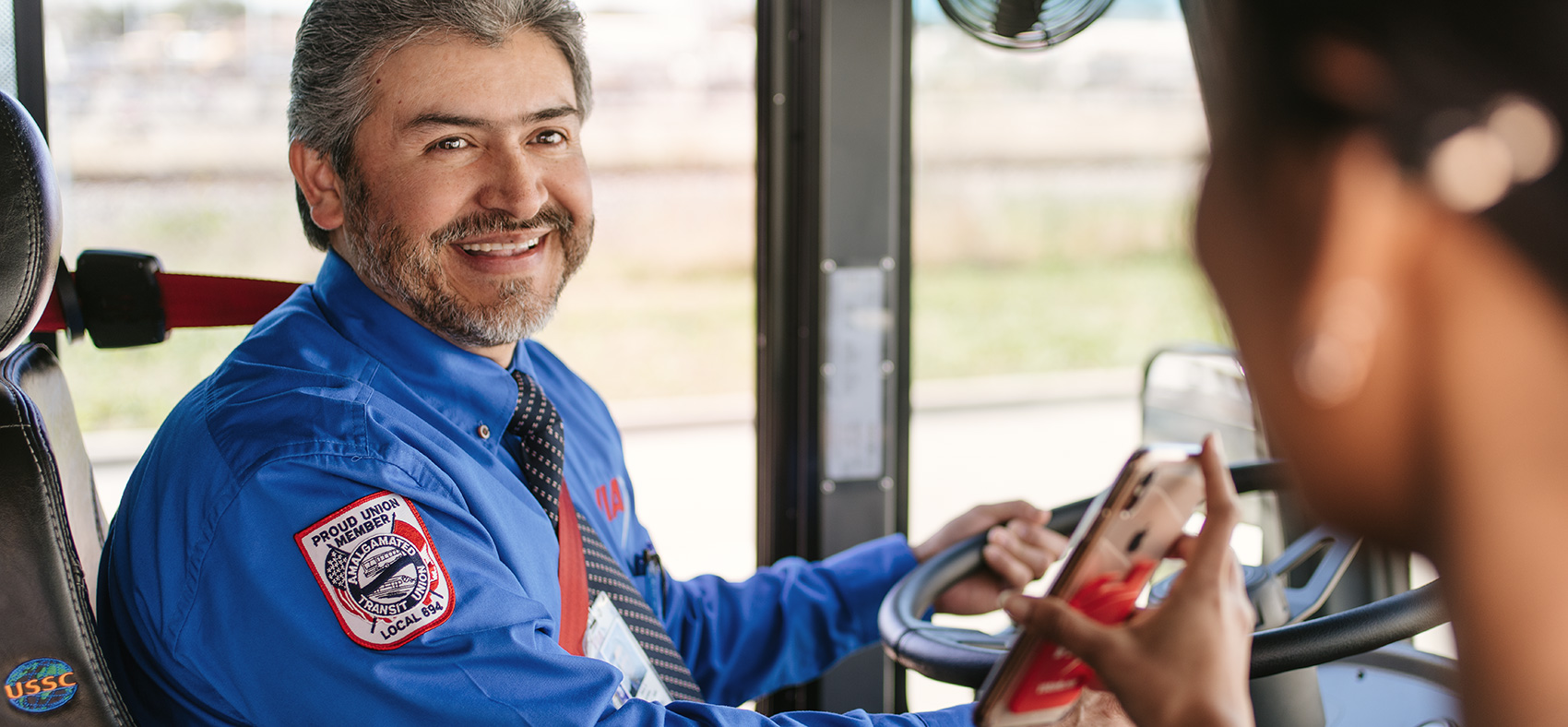Woman using phone to board VIA bus.