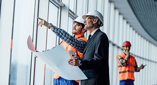 Business team talk with architectural plans, stands on white pan Image: Contract Forum