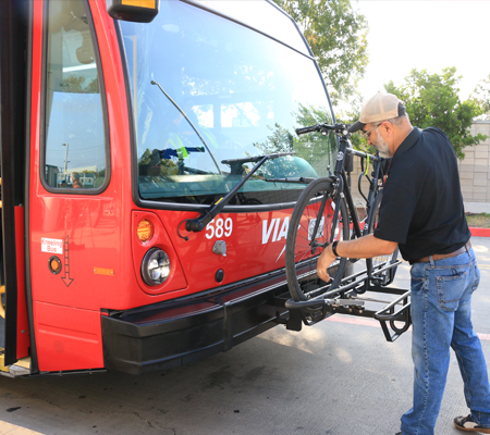 Rider loading bicycle on a VIA bus bike rack.